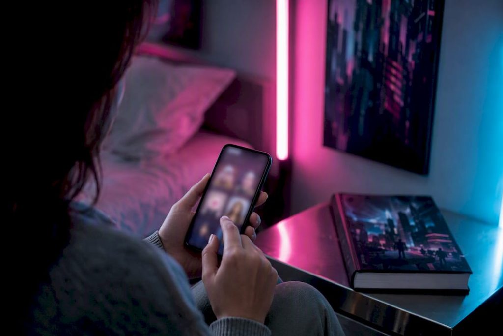 Hands holding smartphone in neon room