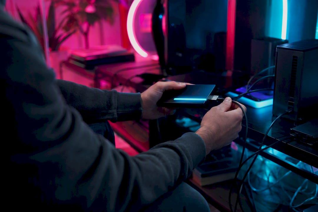 Hands unplugging glowing data device on neon desk